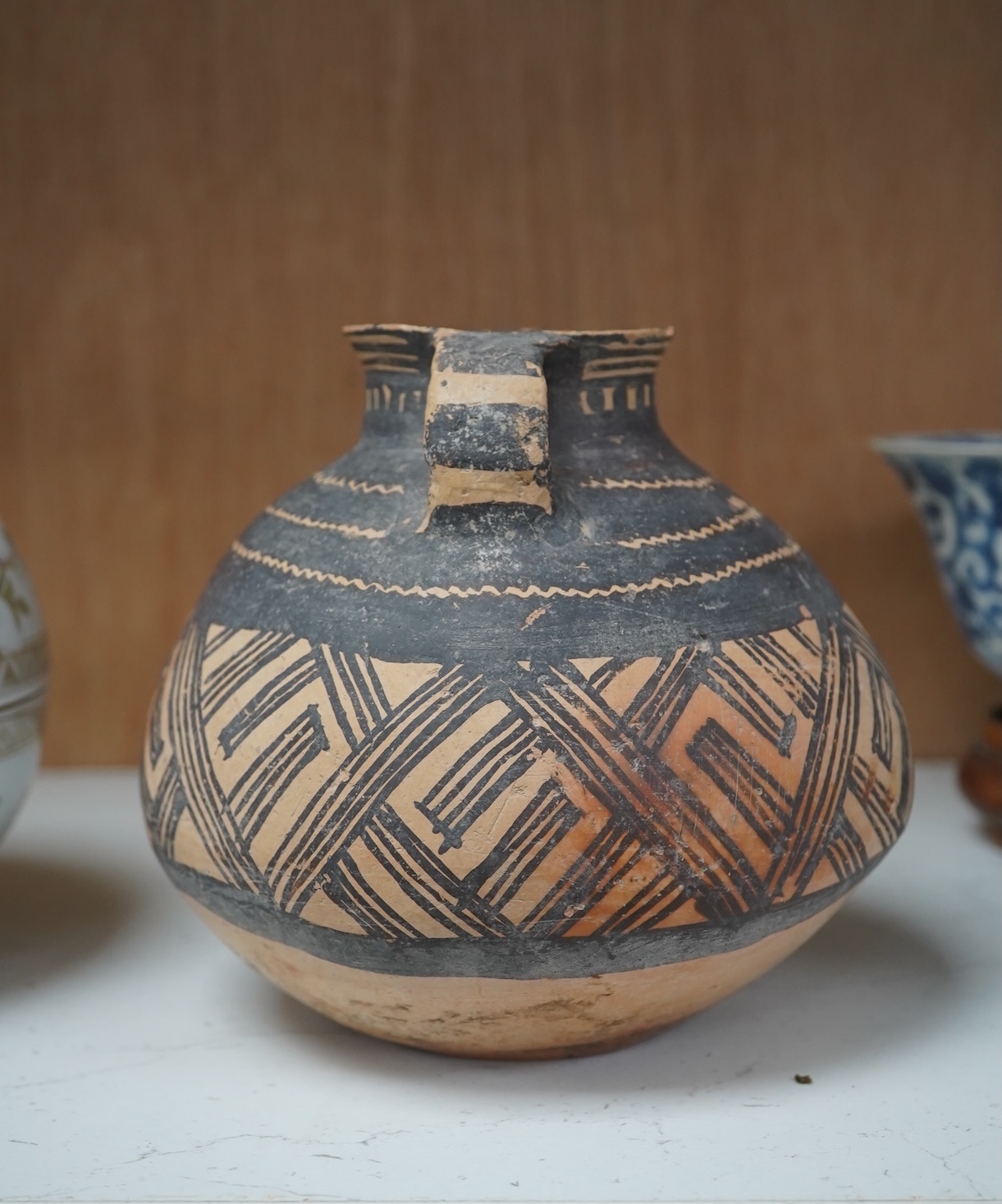 A Chinese neolithic pottery two handled jar - 14cm tall. Condition - fair to good, Provenance: the vendor‘s parents lived in Hong Kong from 1947 and bought the jar from a specialist dealer before 1980.
